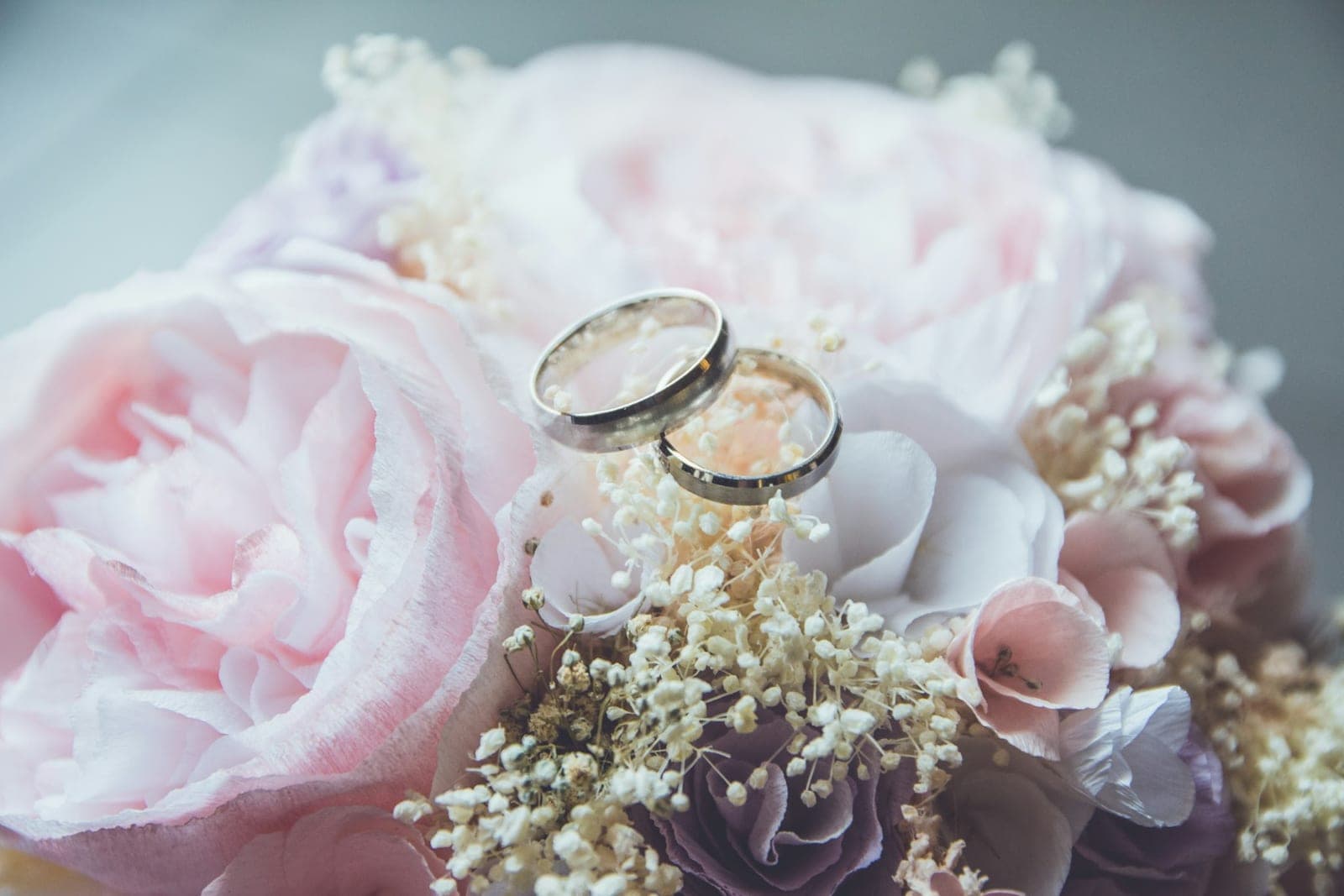 Two wedding rings resting on pale peonies